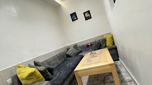 A modern living room with a grey sofa, a wooden coffee table, and a patterned rug. - Maison Calme à Proximité de la mer (Agadir)