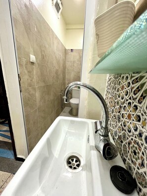 A bathroom with a white sink, a curved faucet, a toilet, and a patterned wall. - Maison Calme à Proximité de la mer (Agadir)