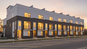 A modern multi-story residential building with a flat roof and large windows.