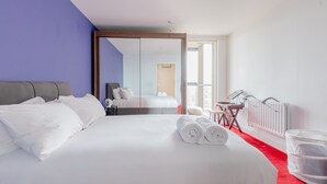 Ein Hotelzimmer mit einem großen Bett, einem Schreibtisch mit Stuhl, einem Heizkörper und einem Fenster mit Aussicht.
