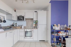 Une cuisine moderne avec des armoires blanches, des appareils en acier inoxydable et un mur d’accent bleu.