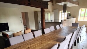A large dining area with a long wooden table and white upholstered chairs.