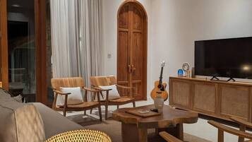 Uma sala de estar moderna com um sofá, cadeiras de madeira, uma mesa de centro, uma televisão e uma guitarra.