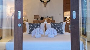 Quarto com uma cama grande, cabeça de touro montada na parede e vista para o exterior.
