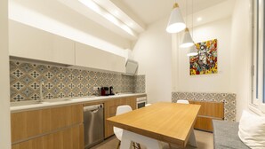 A modern kitchen with wooden cabinets, a stainless steel dishwasher, and a dining area with a wooden table and white chairs. - Via Concezione a Montecalvario 19 - Camera 3 (Naples)