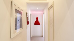 A hallway with framed pictures on the walls, a red silhouette decoration on the wall, and a door on the right. - Via Concezione a Montecalvario 19 - Camera 3 (Naples)