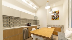 A modern kitchen with wooden cabinets, a stainless steel dishwasher, and a dining area with a wooden table and white chairs. - Via Concezione a Montecalvario 19 - Camera 1 (Naples)