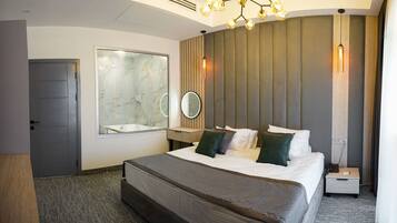 A modern hotel room with a large bed, a mirror, a bedside table, and a unique chandelier.