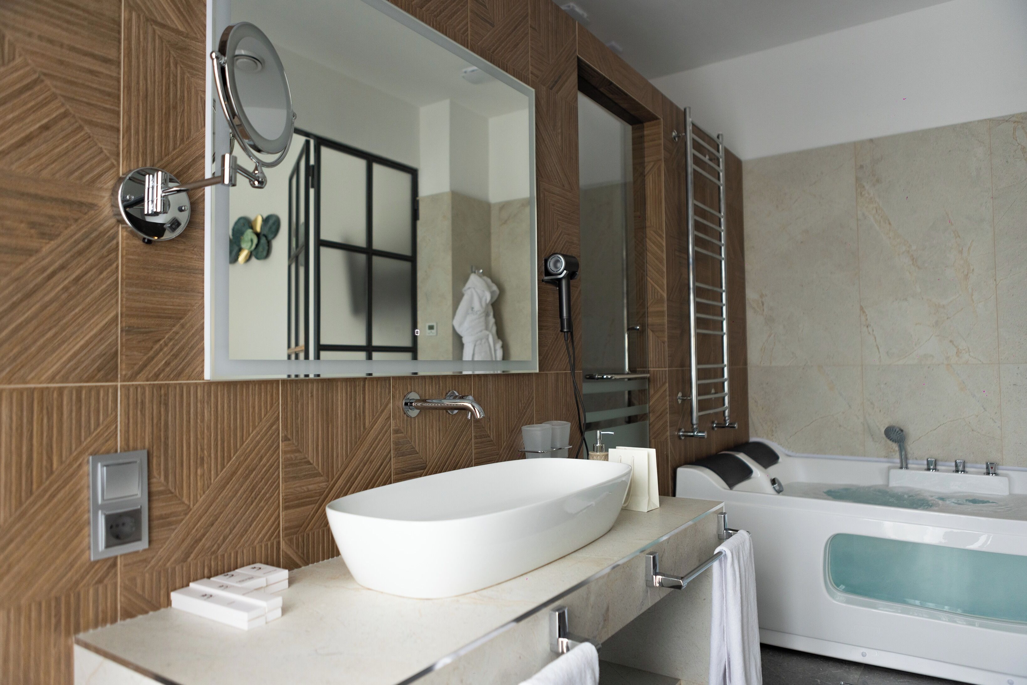 A modern bathroom with a large mirror, a freestanding bathtub, and a vessel sink.