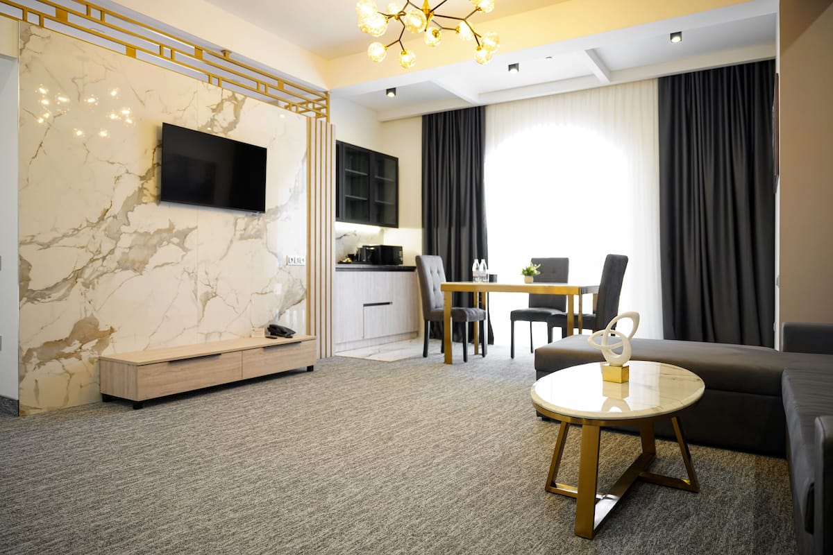A modern living room with a marble wall, a flat-screen TV, a round coffee table, and a sofa.