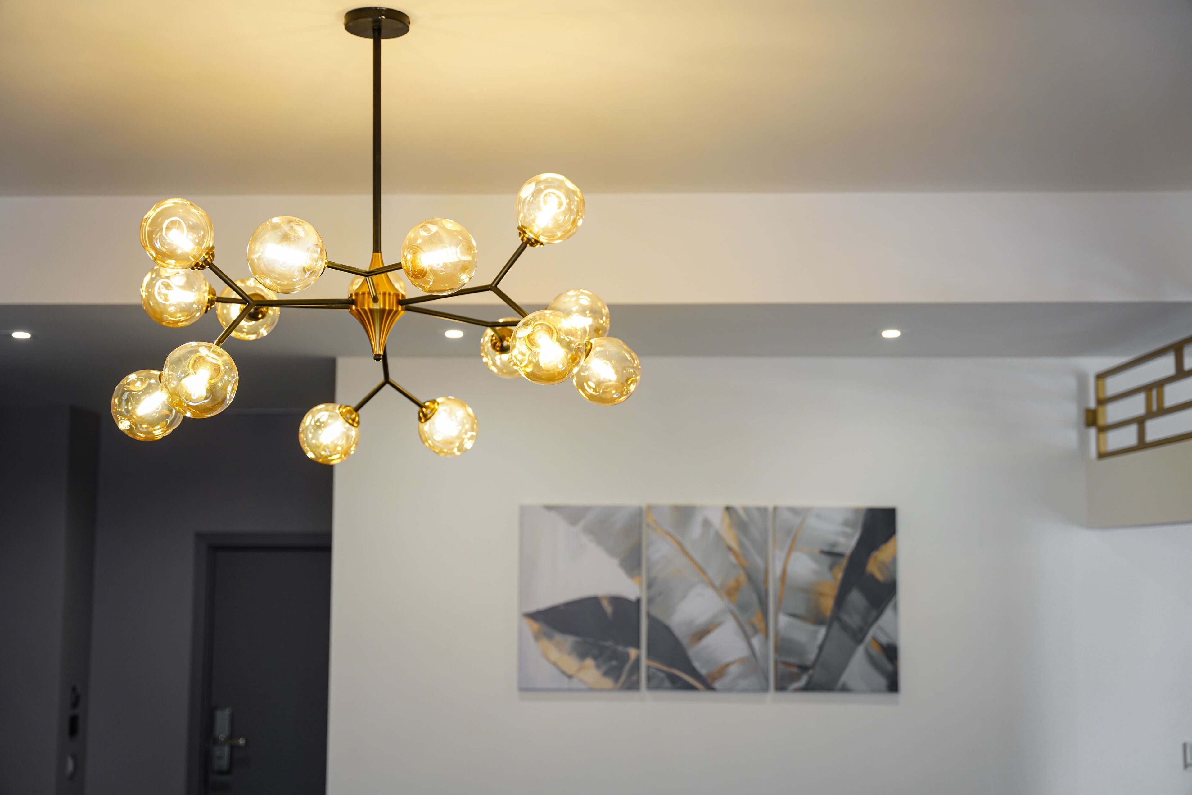Un lustre composé de plusieurs sphères lumineuses suspendues à une structure centrale, dans un intérieur moderne.