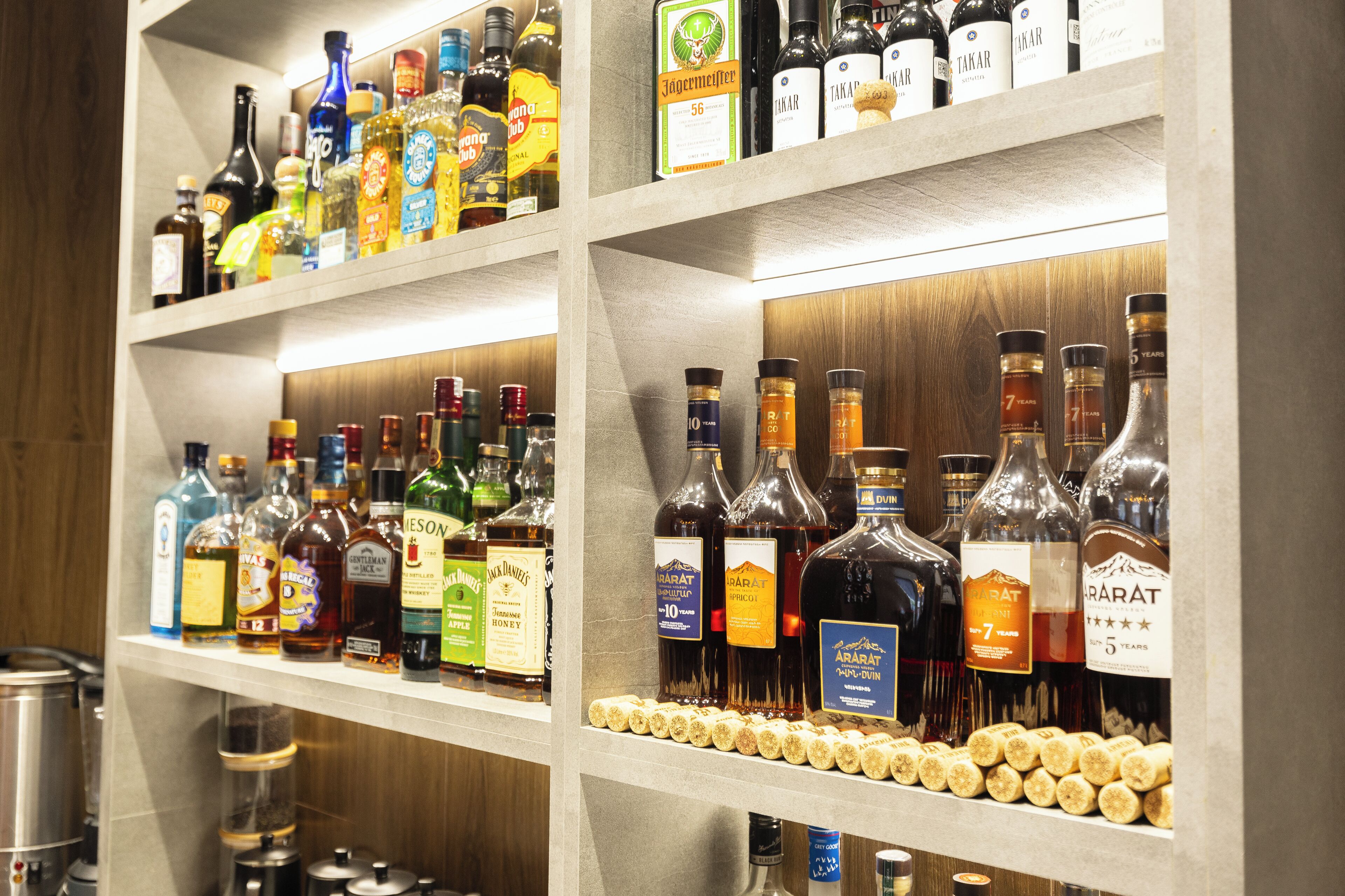 Estantes llenos de botellas de licores y una hilera de corchos de vino.