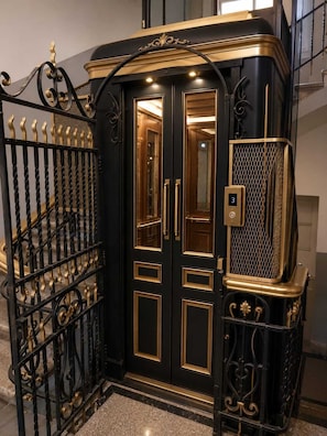 Un ascensor negro con detalles dorados y una pantalla digital que muestra el número 3.