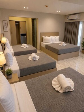 A hotel room with two beds, a minibar, a mirror, and a potted plant. - City View Palace Hotel (Cairo)