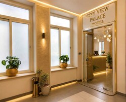 Hotellin sisäänkäynti, jossa on kyltti, jossa lukee ”CITY VIEW PALACE HOTEL”, suuret ikkunat ja ruukuissa olevia kasveja.