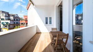 A balcony with a wooden table and chairs, a view of neighboring buildings, and a door leading to an interior space. - Casa del Marchese del Grillo (Rome)