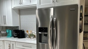 Une cuisine moderne avec des meubles blancs, un réfrigérateur en acier inoxydable et un distributeur d’eau intégré.
