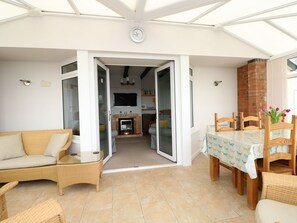 A sunlit patio with a dining area, a sofa, and a fireplace. - Windyridge (Skegness)