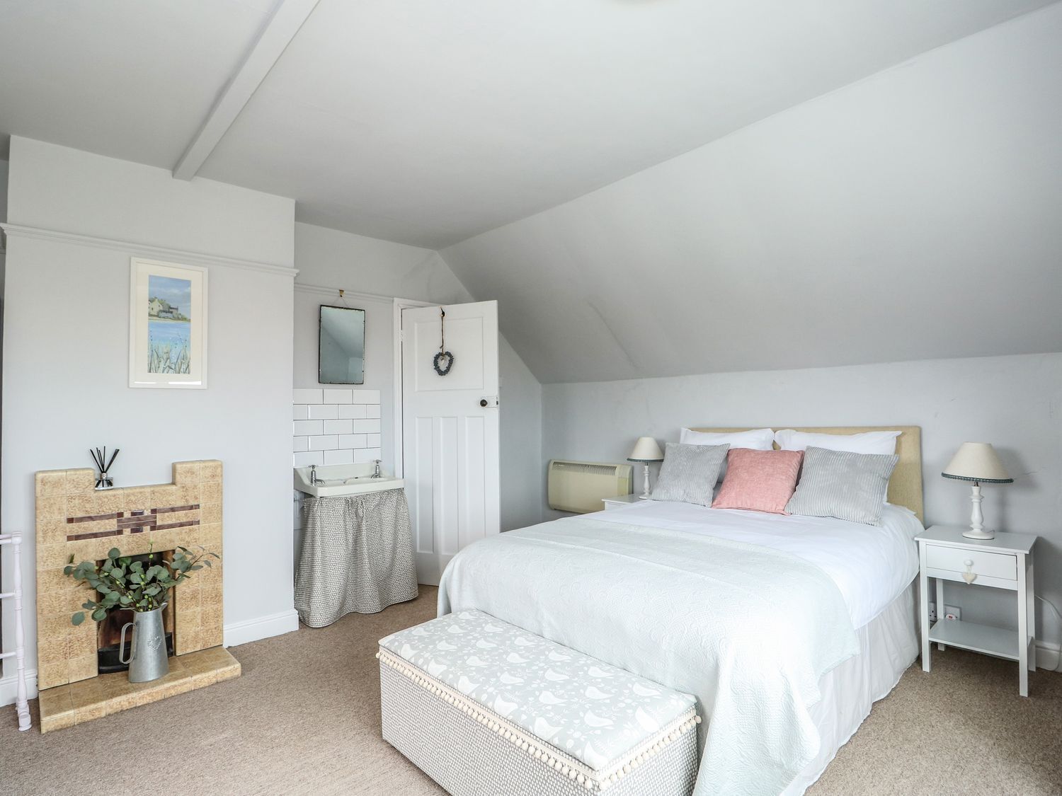 Un dormitorio con una cama grande, una mesita de noche, una chimenea y una puerta que da a otra habitación.