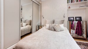Ein Schlafzimmer mit einem großen Bett, einem Kleiderschrank, einem Nachttisch, einem Spiegel und einem Bücherregal.