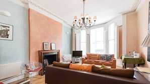 Ein Wohnzimmer mit Sofa, Kamin, Fernseher und einer Chandelier.