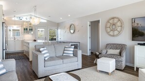 A modern living room with a grey sofa, patterned armchair, and a coffee table. - Dot's Spot, Almost Oceanfront House in Emerald Isle, NC! (Atlantic Beach)
