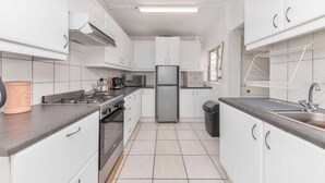 A compact kitchen with white cabinets, a stainless steel refrigerator, a gas stove, and a sink. - Peaceful 1BD Flat w/ Private Gardenrondebosch (Cape Town)