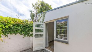 A white building with a door open to a small porch area. - Peaceful 1BD Flat w/ Private Gardenrondebosch (Cape Town)