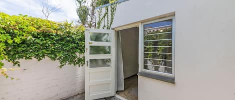 A white building with a door open to a small porch area.