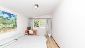 A bedroom with a bed, a desk with a computer, and a window with curtains. - Peaceful 1BD Flat w/ Private Gardenrondebosch (Cape Town)