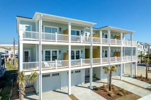 Un immeuble résidentiel à plusieurs étages, doté de balcons, d’un garage et d’un jardin paysager à l’avant.