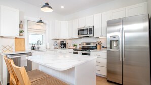 A modern kitchen with white cabinets, stainless steel appliances, and a central island with seating.