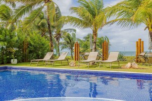 Una piscina al aire libre, sombrillas, sillones reclinables de piscina