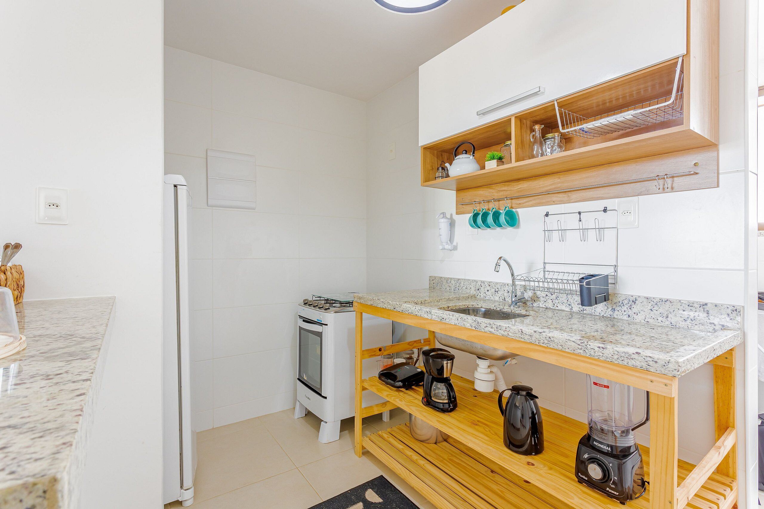 A compact kitchen with a built-in oven, a coffee maker, and a blender on a wooden countertop.