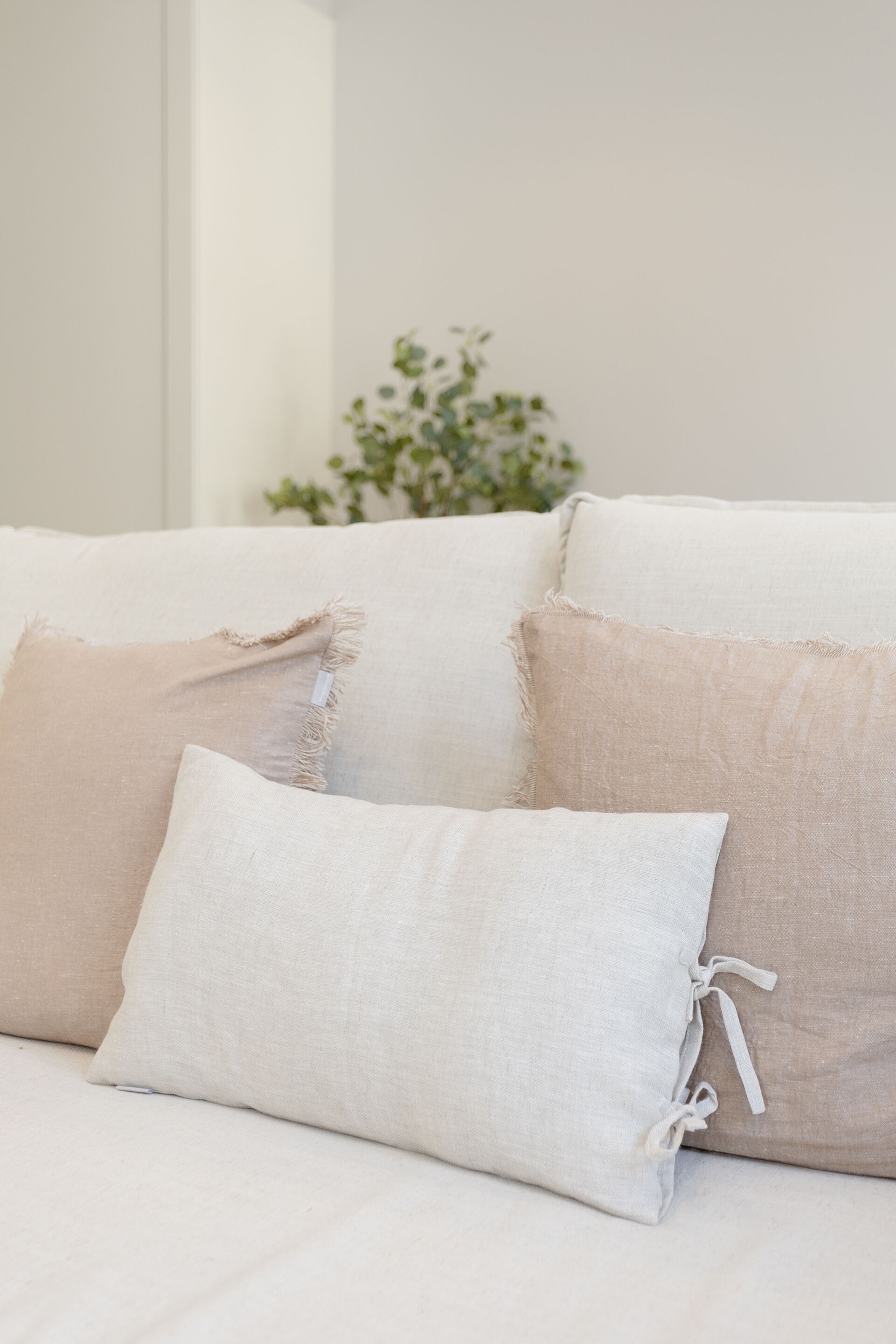 Ein weißes Sofa mit drei Kissen, eines davon hat einen ausgefransten Rand.
