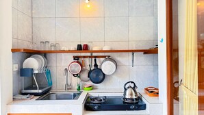 Eine kleine Küche mit Spüle, Herd und hängenden Töpfen.