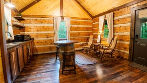 A log cabin interior with a kitchen, dining area, and a cozy seating space.