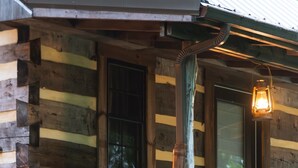 A log cabin with two rocking chairs outside, a porch, and a wooden door.