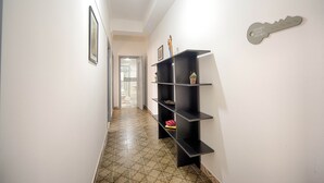 Un pasillo con piso estampado, un estante negro con objetos decorativos y un letrero 'Home Two Home' en la pared.