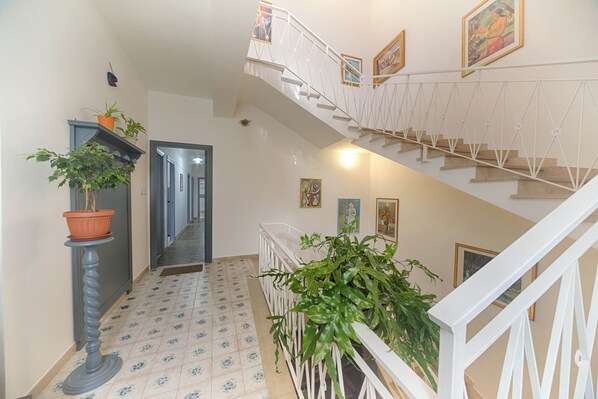 A staircase with white railings, a tiled floor, and potted plants.