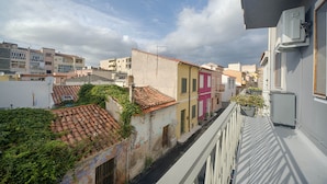 Una calle estrecha flanqueada por edificios, algunos con balcones y otros con ventanas al nivel de la calle.