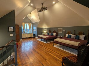 Une chambre avec deux lits, un lustre, une commode en bois et une vue par la fenêtre.