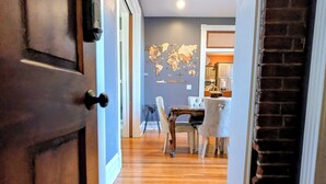 A hallway with wooden flooring leading to a dining area with a table and chairs. - Studio + 3rd Floor Access (Washington)