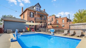 A rectangular swimming pool with a blue interior, surrounded by a concrete deck. There are lounge chairs and a basketball hoop near the pool. - Studio + 3rd Floor Access (Washington)