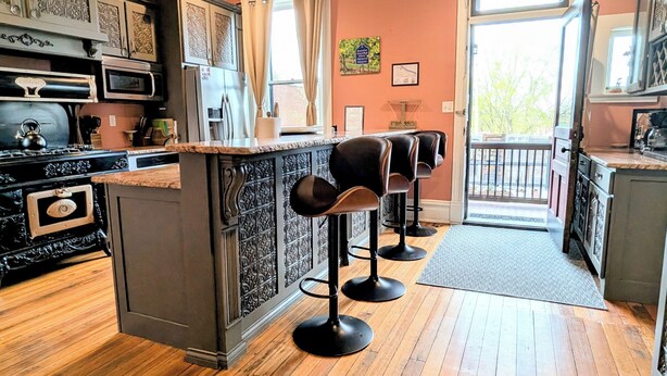 A kitchen with a bar area, wooden floors, and a chandelier. - Studio + 3rd Floor Access (Washington)