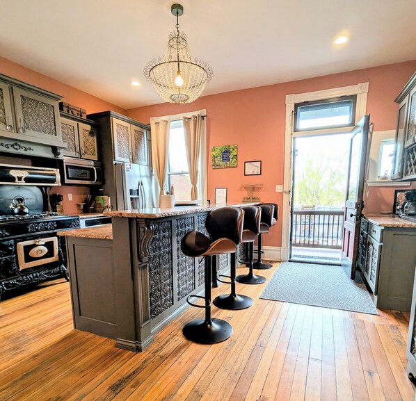 Une cuisine avec un coin bar, un plancher en bois et un lustre.