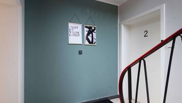 A hallway with teal walls, two framed motivational posters, a black metal handrail, and a door labeled with the number 2.