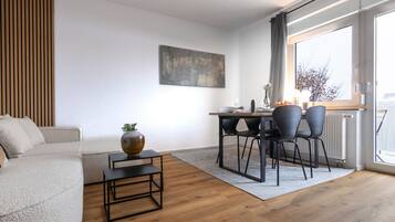 Ein modernes Wohnzimmer mit einer Couch, einem Couchtisch und einem Essbereich mit Stühlen und einem Tisch.