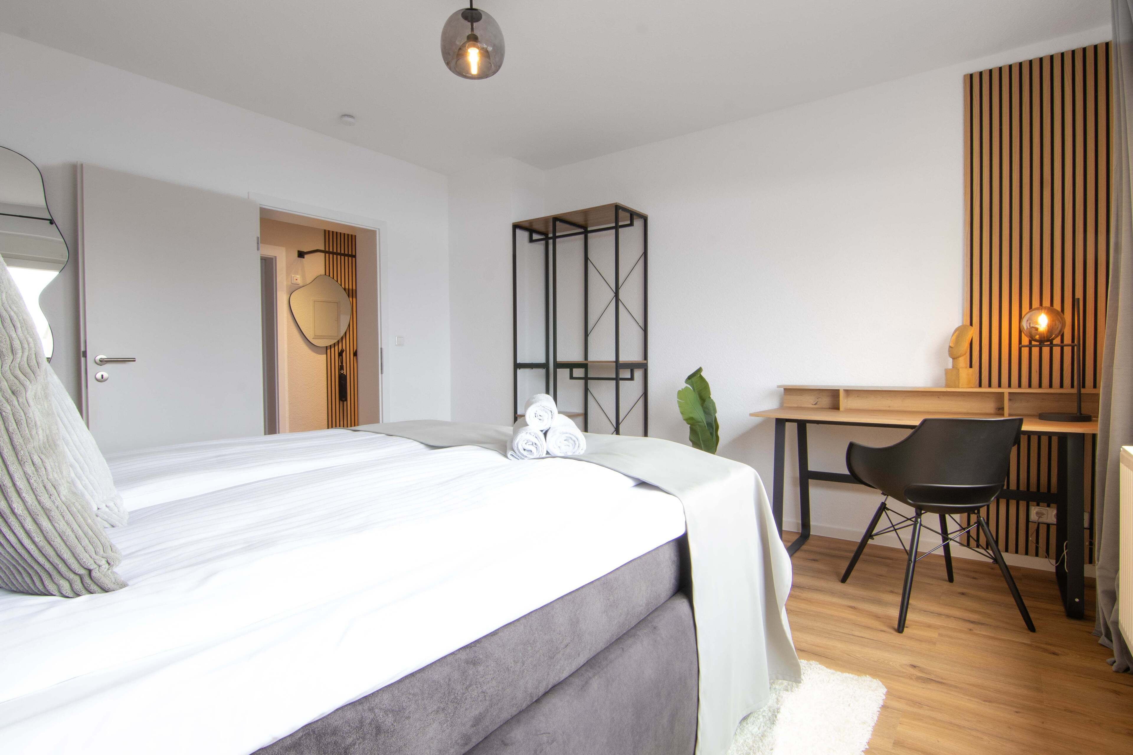Un dormitorio moderno con cama, escritorio y silla.