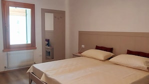 Un dormitorio con cama, mesita de noche, cómoda y ventana.